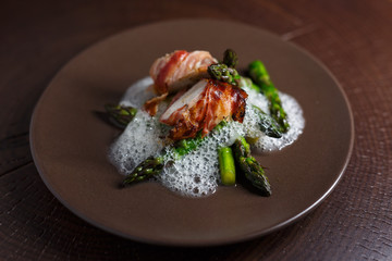 Spargel mit Huhn im Speckmantel auf braunem Teller