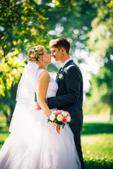 portrait the bride and groom on the background of the park alley