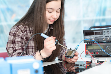 The girl adjusts the electronics  system on the microprocessor