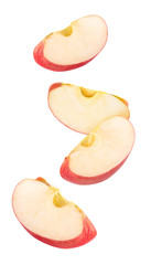 Isolated flying apple wedges. Four falling pieces of red apple fruit isolated on white background with clipping path