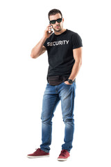 Fototapeta premium Tough serious undercover policeman talking on the phone looking at camera. Full body length portrait isolated on white studio background. 