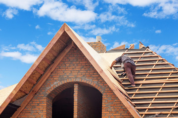 House under construction. Workers installing fibreboard on the roof