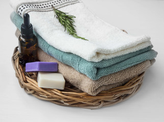 Spa towels still life on wicker tray with essential oil bottle and natural soap