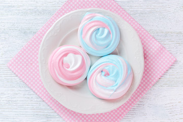 meringues in pastel colors with abstract pattern on a plate and a pink serviette