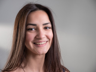 Naklejka premium Attractive young woman with happy eyes stands and smiles in studio