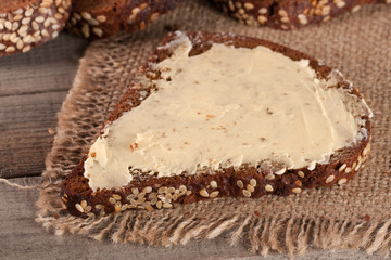 slices of black bread with sesame seeds and butter on the old wooden background