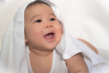 Little baby smiling under a white towel