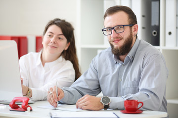 Man and woman teamwork in the office. The girl is looking at the monitor, and the man is in the camera