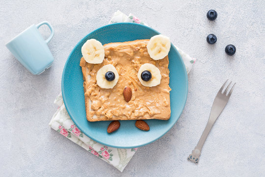 Cute, Healthy And Funny Breakfast For Kids: Peanut Butter Toast With Banana And Blueberries Shaped As Owl. Top View