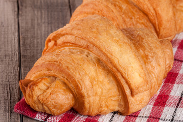 One croissant on a wooden table with a napkin
