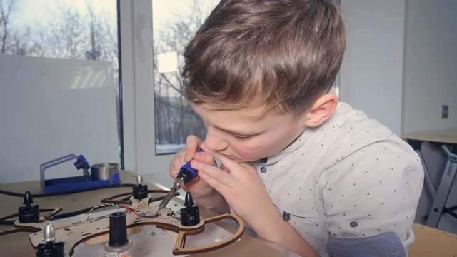 Boy soldering chip of drone aircraft. 4K.