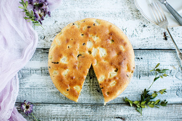 Homemade pie on a wooden background, in a rustic style, with gauze and flowers, top view
