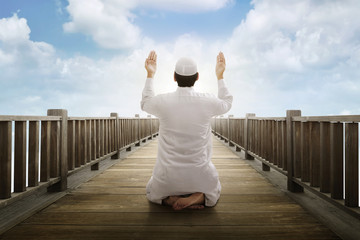 Young asian muslim man raising hand and praying