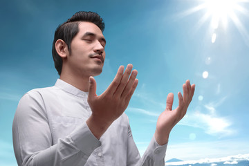 Naklejka premium Handsome asian muslim man raising hand and praying