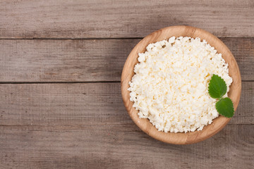 Cottage cheese in a wooden bowl on old wooden background with copy space for your text. Top view