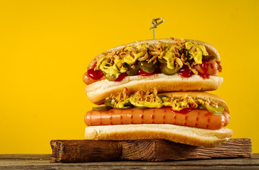 Tasty classic traditional hot dog on wooden board on yellow background.