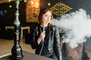 A beautiful young girl rests after a hard day's work, and smokes a hookah in cafe