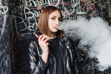 Obraz na płótnie Canvas Portrait of a beautiful young girl with vape. Vaping concept
