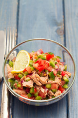 tuna salad with tomato and pepper in bowl on blue background