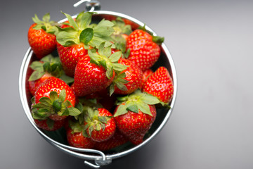 Strawberries in an aluminum bucket on black