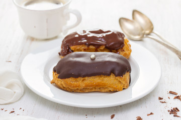chocolated eclairs on white dish on wooden background