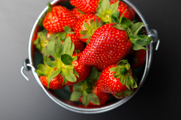 Strawberries in an aluminum bucket on black
