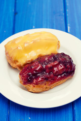eclairs on white dish on wooden background