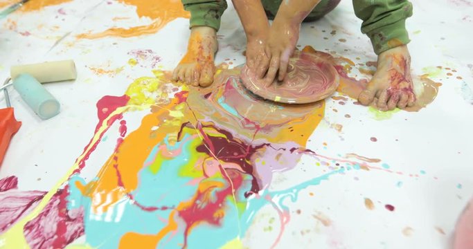 Child being busy covering her body with colorful paint