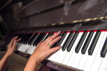 Young woman hands playing on piano (shallow DOF)