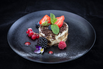 Tiramisu cake on the black plate