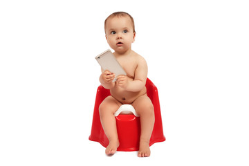 Infant child baby toddler sitting on potty toilet stool pot with phone isolated on a white background - obrazy, fototapety, plakaty