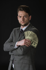 young businessman holding dollar banknotes fan isolated on black