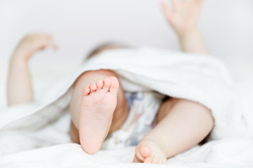 Baby feet under the towel.Baby lying in diaper on the bed, unrecognizable baby.Shallow doff