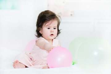 Fototapeta na wymiar Sweet baby little girl sitting on bed , playing with a balloons.Shallow doff, copy space
