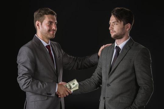 Businessmen shaking hands with dollar banknotes isolated on black