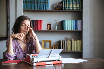 Portrait of a tired woman journalist sitting at the table