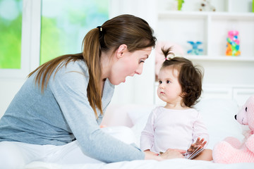 Baby little girl looking at mom while she reading the interesting story from the book.Shallow doff