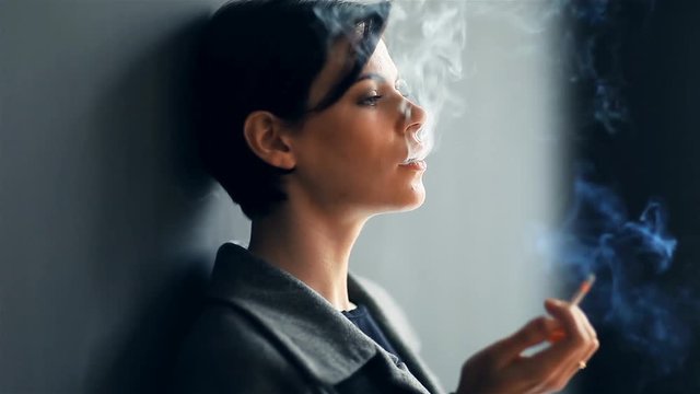 Beautiful fashionable woman smoking a cigarette