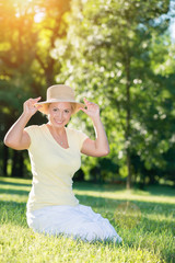 Fototapeta premium Happy, blonde woman with a hat posing in the sunset park.Lens flare