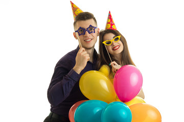 beautiful loving couple carrying balloons and colored glasses and smiling