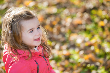 Portrait of smiling little girl in autumn park. Shallow doff, copy space.