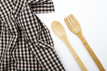 Background of plaid kitchen tablecloth and wooden cutlery on white background. Copy space. Kitchen.