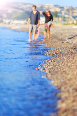A man and a woman, a young couple, in love, walk along the seashore, in the summer, happy. Shallow depth of field, the background is artistically blurred by the lens