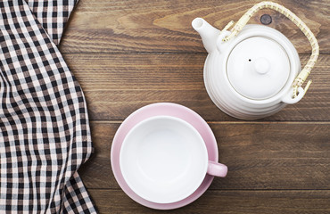 Background of checkered napkin next to ceramic ware on wooden background. Horizontal shoot.