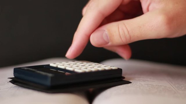 Hand with calculator on book