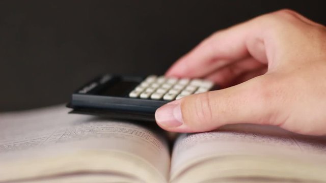 Hand with calculator over the book