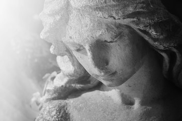 Vintage image of a sad angel on a cemetery against the background of leaves