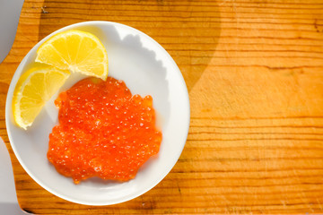 Closeup on person eating red caviar delicacy from white plate, closeup light macro background