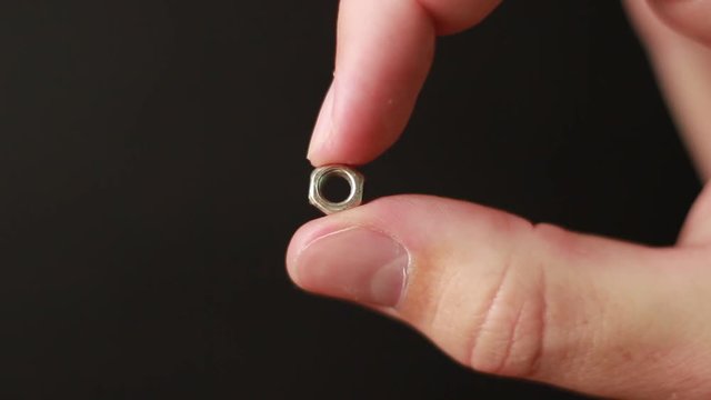 Small steel nut in hand closeup