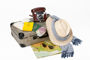 Preparing for a journey. Vintage suitcase with a map, travel documents, a hat, money and...